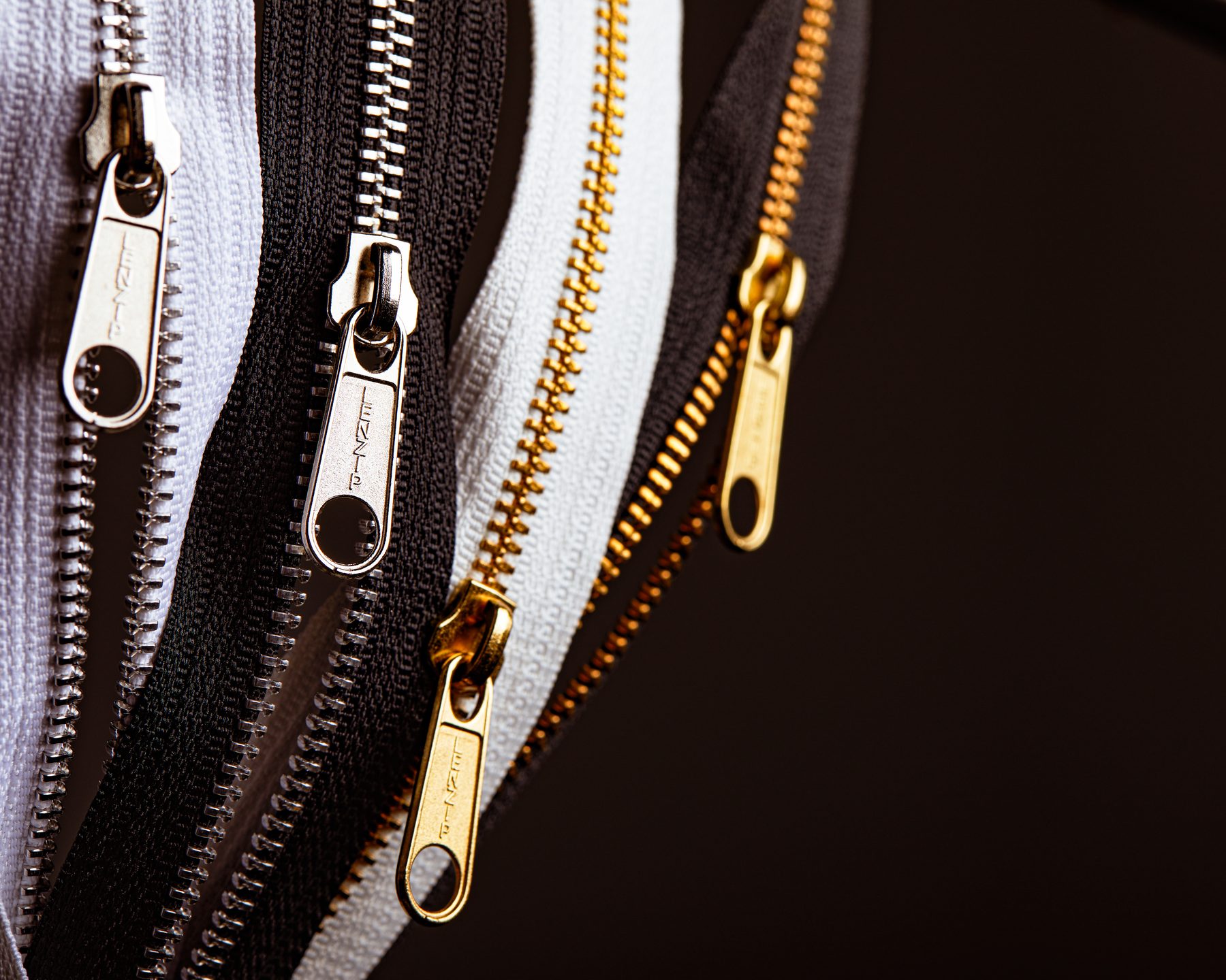 Four Lenzip metal zipper chains with branded sliders
