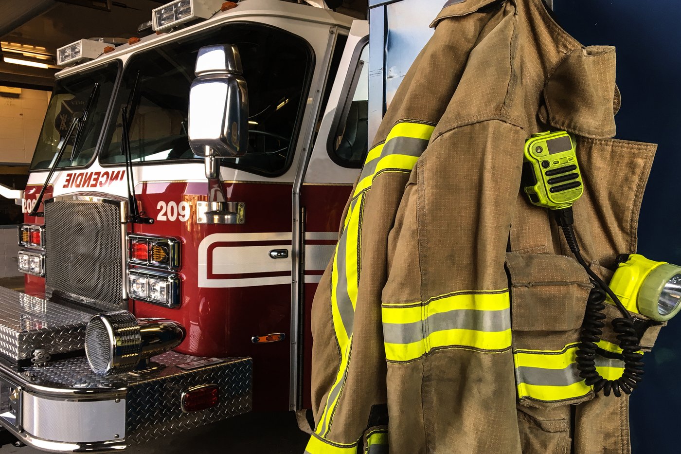 Firefighter turnout jacket with reflective stripes beside a fire engine
