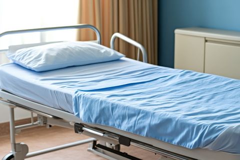 Hospital bed with light blue linens in a patient room