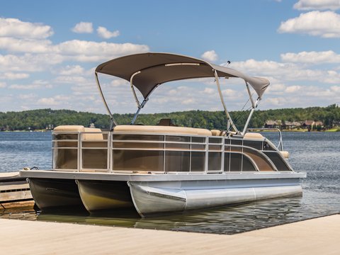 Pontoon boat with bimini on a lake dock