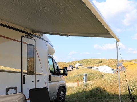 RV parked beneath an awning at a campsite