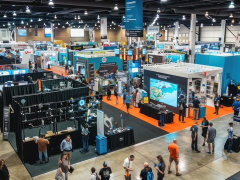 Busy trade show floor with exhibition booths and displays