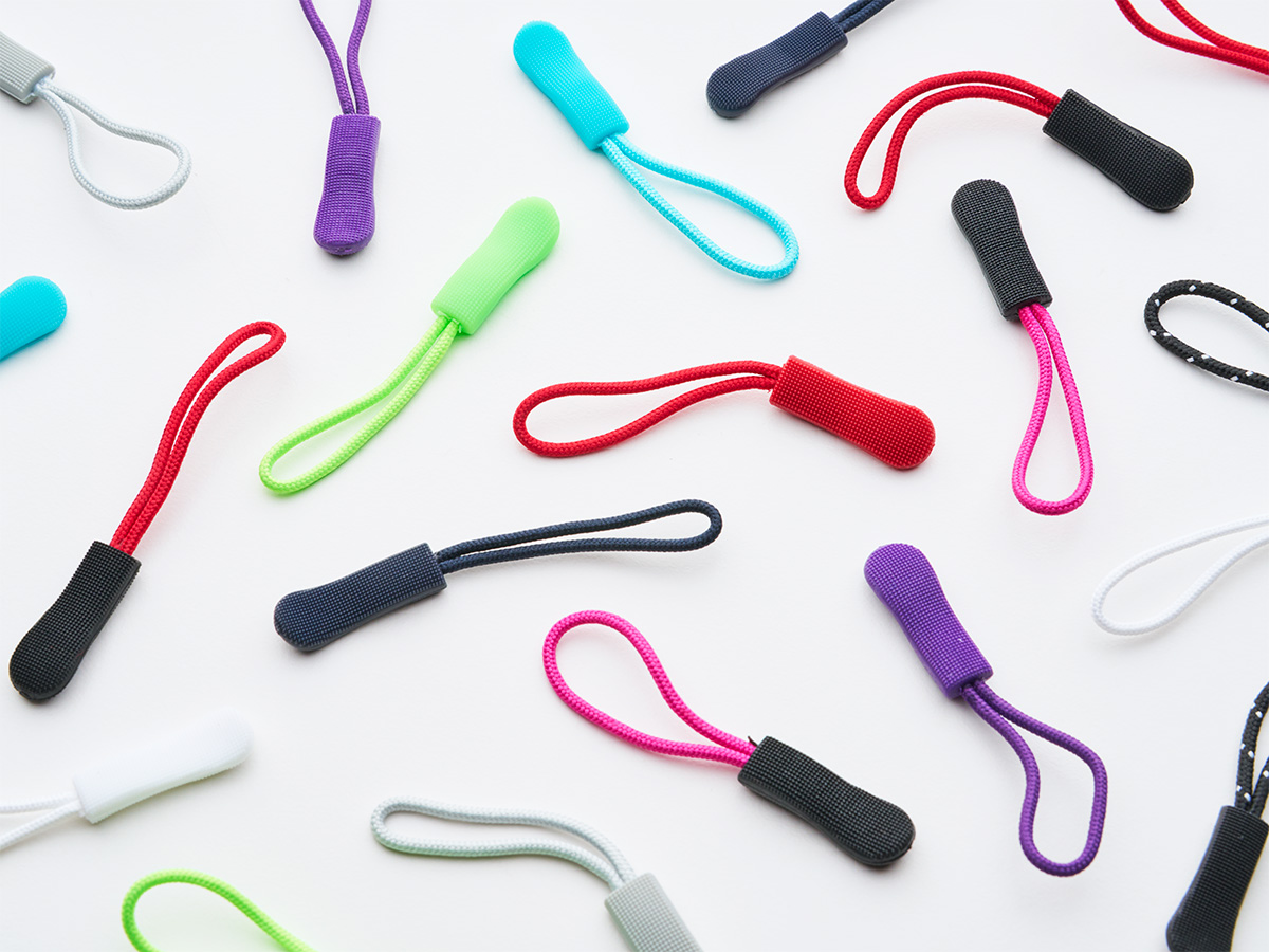 Assortment of colorful Lenzip zipper pull extensions on white
