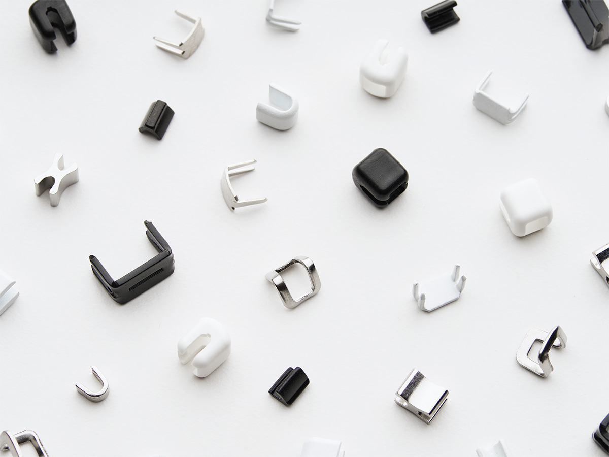 Assortment of Lenzip zipper top and bottom stops in black, white, and metal